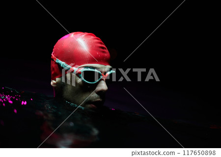 A determined professional triathlete undergoes rigorous night time training in cold waters, showcasing dedication and resilience in preparation for an upcoming triathlon swim competition A determined professional triathlete undergoes rigorous night time training in cold waters, showcasing dedication and resilience in preparation for an upcoming triathlon swim competition 117650898