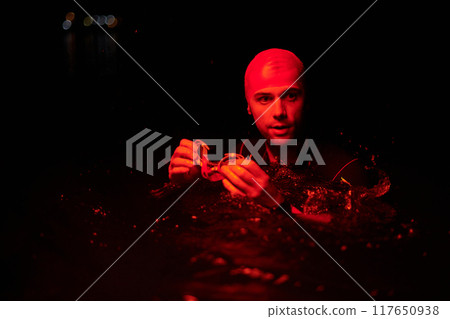 Authentic triathlete swimmer having a break during hard training on night neon gel light Authentic triathlete swimmer having a break during hard training on night neon gel light 117650938