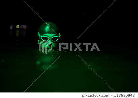 Authentic triathlete swimmer having a break during hard training on night neon gel light Authentic triathlete swimmer having a break during hard training on night neon gel light 117650948
