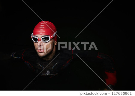 A determined professional triathlete undergoes rigorous night time training in cold waters, showcasing dedication and resilience in preparation for an upcoming triathlon swim competition 117650961
