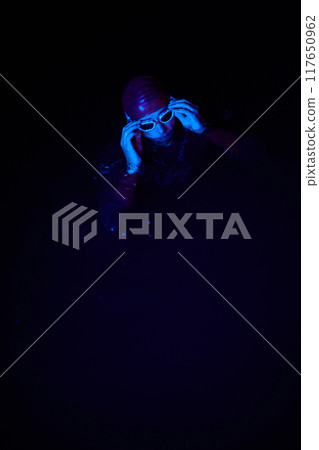 Authentic triathlete swimmer having a break during hard training on night neon gel light 117650962