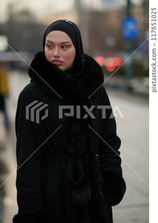 Muslim woman walking on an urban city street on a cold winter night wearing hijab 117651025