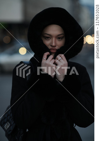 Muslim woman walking on an urban city street on a cold winter night wearing hijab 117651028