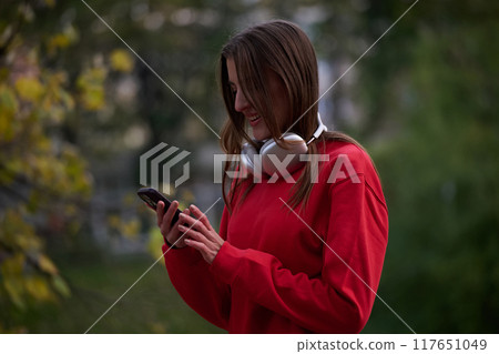 Sporty woman checks smartphone before doing some exercises listens music from a playlist Sporty woman checks smartphone before doing some exercises listens music from a playlist 117651049