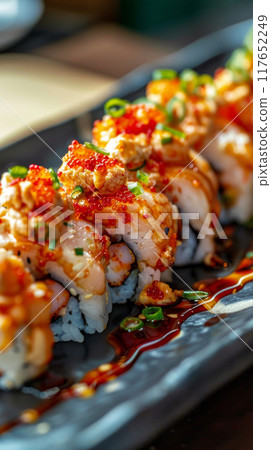 Savor the bold flavors of Volcano rolls featuring a spicy scallop mixture atop California rolls, baked to perfection and garnished with vibrant tobiko and finely chopped green onions 117652249