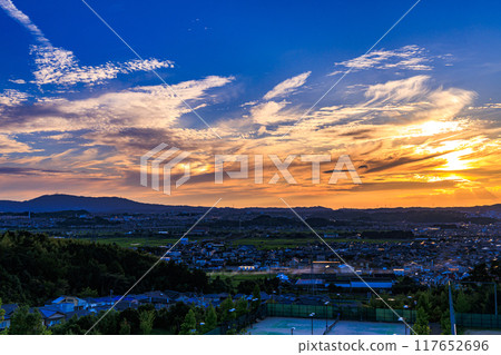 Evening view from a hill overlooking the town of Kizu in Kizugawa City, the southernmost part of Kyoto Prefecture. The sun sets over the Ikoma mountain range, painting the mountainside golden #4 117652696