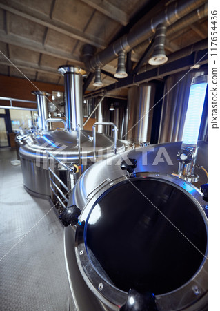 The stainless steel tanks in the brewery, with their advanced valves, highlight the technical expertise required in modern brewing. The stainless steel tanks in the brewery, with their advanced valves, highlight the technical expertise required in modern brewing. 117654436