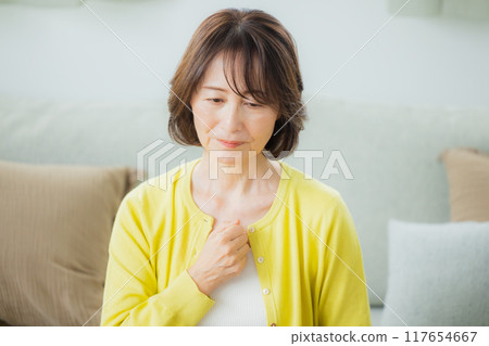Middle-aged woman in living room feeling unwell 117654667