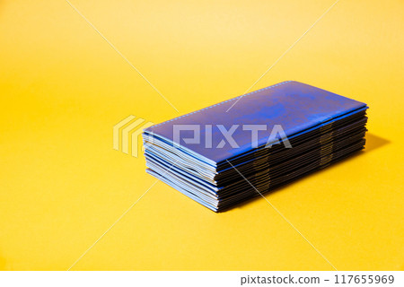 Stack of blue brochures on yellow background Stack of blue brochures on yellow background 117655969