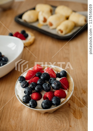 Delicious dessert bowl with fresh berries served on a wooden tabletop in a cozy kitchen setting Delicious dessert bowl with fresh berries served on a wooden tabletop in a cozy kitchen setting 117656089