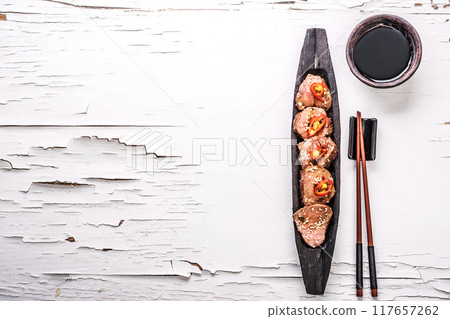 Oriental spicy meat on wooden plate on white background 117657262