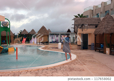 Dolsan-eup, Yeosu-si, South Korea - July 26, 2024: Young woman watching sunrise at a resort with a swimming pool overlooking the sea in Yeosu 117658002