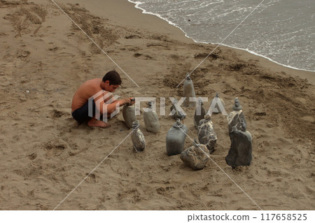 Children plays on the beach sand mounting zen stone Towers before returning to school. Children plays on the beach sand mounting zen stone Towers before returning to school. 117658525
