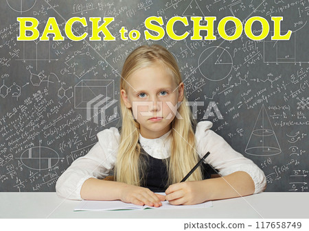Sad child girl pupil in classroom against white Back to school inscription on blackboard background Sad child girl pupil in classroom against white Back to school inscription on blackboard background 117658749