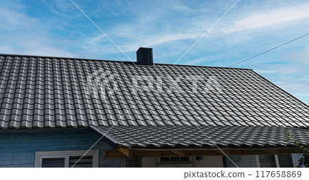 Close-up house roof with steel roofing sheet. Black modular tile effect roof panel. Traditional metal shingle tiles. Profiled metallic corrugated pantile as clay or concrete slate. Building's covering Close-up house roof with steel roofing sheet. Black modular tile effect roof panel. Traditional metal shingle tiles. Profiled metallic corrugated pantile as clay or concrete slate. Building's covering 117658869