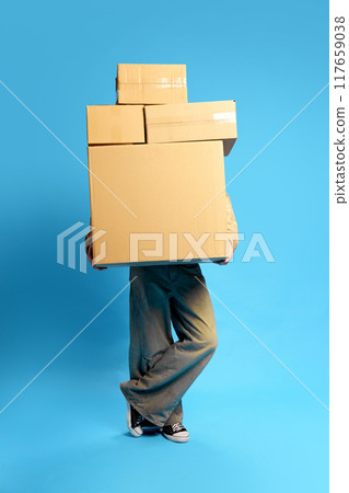 Juggling multiple deliveries, person almost completely hidden behind towering stack of cardboard boxes. Concept of Black Friday sale. Juggling multiple deliveries, person almost completely hidden behind towering stack of cardboard boxes. Concept of Black Friday sale. 117659038