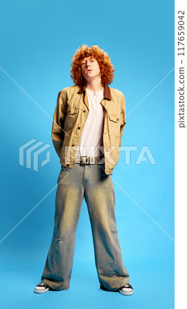 Ready to shopping. Stylish young man, student with curly, red hair posing dressed stylish vintage outfit against blue studio background. Concept of Black Friday sale. 117659042