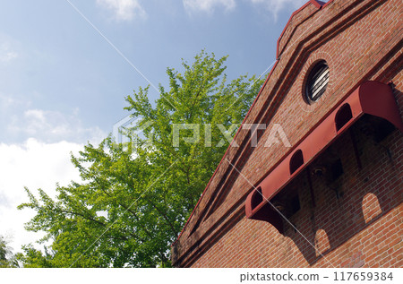 An elegant brick building stands on an old road. It was a decommissioned power plant. On a summer day, it quietly blended into the rural scenery. An elegant brick building stands on an old road. It was a decommissioned power plant. On a summer day, it quietly blended into the rural scenery. 117659384