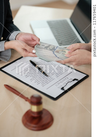 A person is handing over a stack of money to another person 117659401