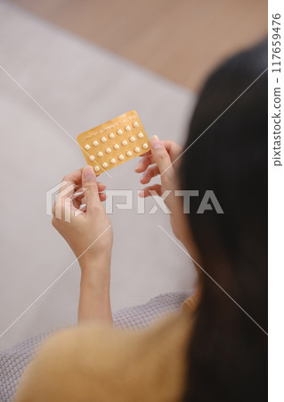 A woman is holding a pack of birth control pills A woman is holding a pack of birth control pills 117659476