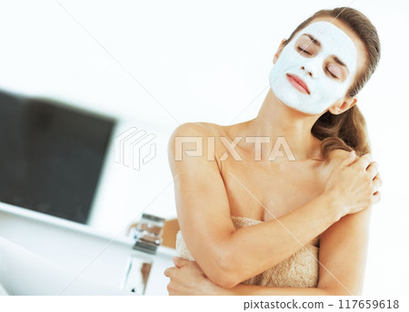 young woman with facial cosmetic mask in bathroom 117659618
