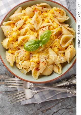 Conchiglie pasta with creamy corn cheese closeup in the bowl. Vertical top view Conchiglie pasta with creamy corn cheese closeup in the bowl. Vertical top view 117659947