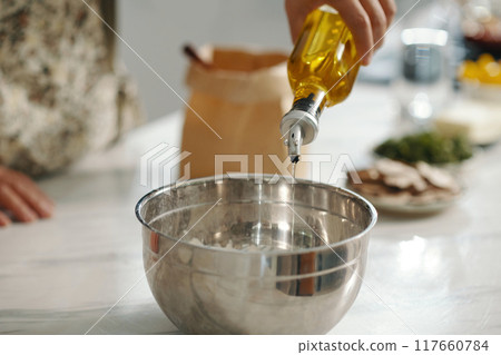 Housewife Pouring Oil In Bowl To Make Dough Housewife Pouring Oil In Bowl To Make Dough 117660784