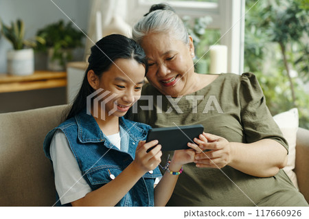 Girl Watching Photo On Smartphone With Her Grandma Girl Watching Photo On Smartphone With Her Grandma 117660926