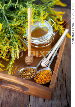 Bee pollen granules. Fresh honey on wooden table. Bee product. Wooden spoon glass. Bee pollen granules. Fresh honey on wooden table. Bee product. Wooden spoon glass. 117661140