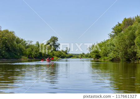 Kayaking on a picturesque river. Entertainment and recreation on a weekend Kayaking on a picturesque river. Entertainment and recreation on a weekend 117661327