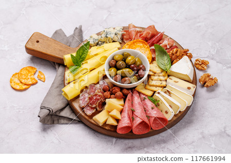 A selection of various cheeses and meats arranged on a wooden board 117661994