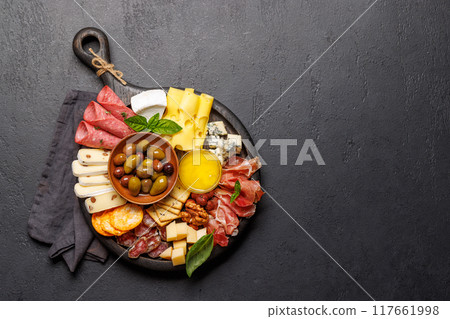 A selection of various cheeses and meats arranged on a wooden board 117661998