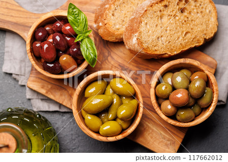 An assortment of various olives presented in a bowl, showcasing different colors, textures, and flavors 117662012