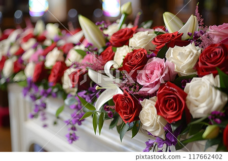 A lovely dark wood coffin adorned with roses, lilies, and carnations creates a lush display. Shot up close, the image captures intricate details, enhanced by soft, diffused light for a warm atmosphere A lovely dark wood coffin adorned with roses, lilies, and carnations creates a lush display. Shot up close, the image captures intricate details, enhanced by soft, diffused light for a warm atmosphere 117662402