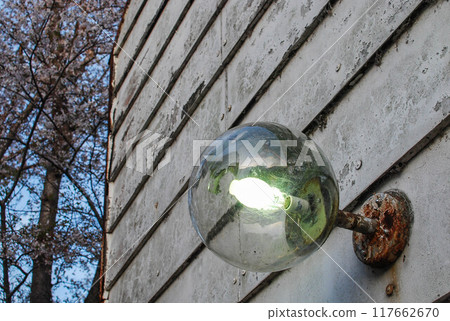 Round glass street lamp shining during the day 117662670