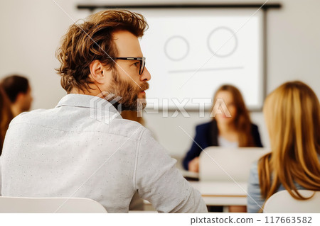 Group of multiethnic people, students sitting in well-lit university auditorium, listening to lecturer 117663582