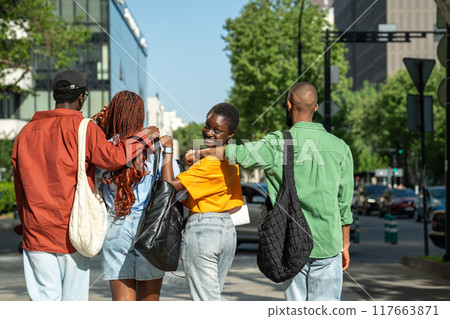 Happy African American friends students hugging walking down street stroll around city after classes 117663871