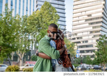 Joyful contented african american young man smiling hugging friend woman while nice meeting in city. Joyful contented african american young man smiling hugging friend woman while nice meeting in city. 117663921