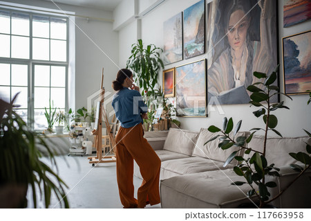 Woman looking at painting, Artist creative studio. Artist apartment gallery interior, Artwork hobby Woman looking at painting, Artist creative studio. Artist apartment gallery interior, Artwork hobby 117663958