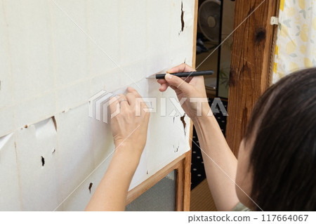 A woman's hands replacing a torn shoji screen A woman's hands replacing a torn shoji screen 117664067
