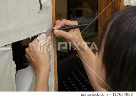 一名婦女的手正在更換破損的障子屏風 一名婦女的手正在更換破損的障子屏風 117664068
