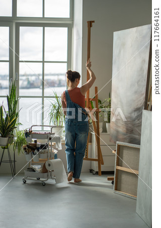 Woman painter thoroughly prepare workplace for further productive work on large creative art project Woman painter thoroughly prepare workplace for further productive work on large creative art project 117664161