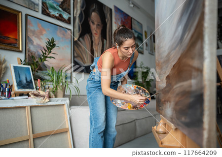 Pensive contemporary artist woman working on creative project expresses different emotions feelings Pensive contemporary artist woman working on creative project expresses different emotions feelings 117664209