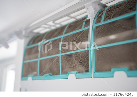 Closeup of dirty dust air conditioner filter on wall. Home air conditioner maintenance 117664243