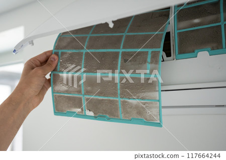 Male removing dirty dusty air conditioner coarse filter for washing, cleaning. Dust cause of illness 117664244
