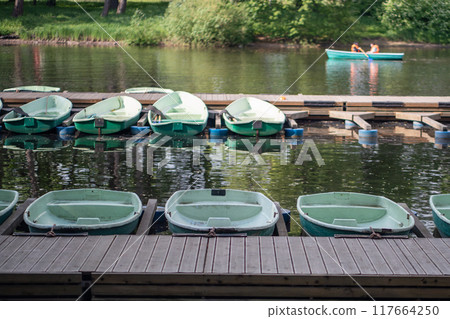 Public park with boats for rent parked on water by bridge. Active nature recreation, outdoor rest Public park with boats for rent parked on water by bridge. Active nature recreation, outdoor rest 117664250