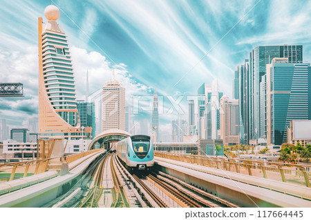 Metro road among glass skyscrapers in Dubai. Metropolitan railway among modern glass skyscrapers in Dubai. Traffic on street in Dubai. Urban background. Altered sky 117664445