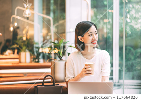 Asian woman holding coffee cup looking out the window at cafe city break weekend balance lifestyle Asian woman holding coffee cup looking out the window at cafe city break weekend balance lifestyle 117664826