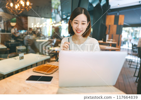 Asian woman using laptop and waiting at coffee cafe city break weekend balance lifestyle Asian woman using laptop and waiting at coffee cafe city break weekend balance lifestyle 117664839