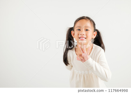 Exuberant young kid girl showcases the OK sign with an optimistic smile, conveying agreement and positivity isolated on a white background, ideal for your text customization. kindergarten child smile 117664998